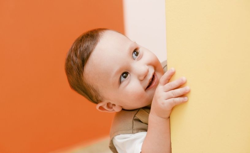 オレンジの壁をバックにほほ笑む赤ちゃん